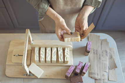 Hands wrapping freshly cut handmade soap bars.